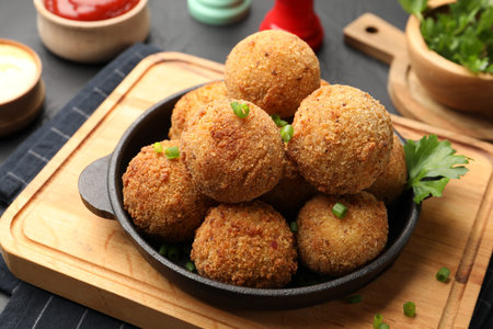 Delicious fried croquette balls with parsley and green onion on gray table, closeup