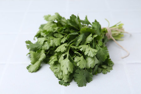 Bunch of fresh aromatic cilantro on white tiled table, closeup
