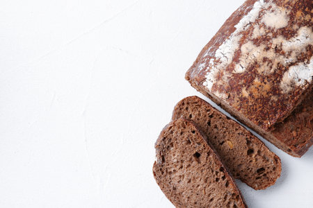 Pieces of fresh rye bread on white textured table, top view. Space for text