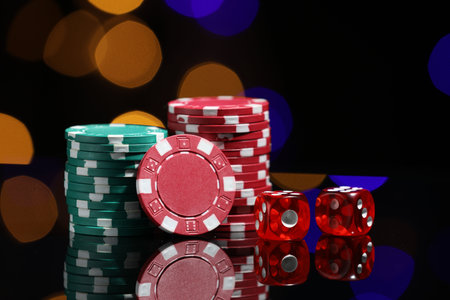 Casino chips and dice on mirror surface against blurred lights, closeupの写真素材