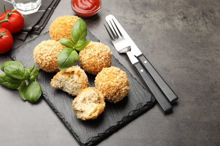Delicious fried croquette balls with basil on gray textured table, closeup