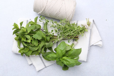 Different fresh green herbs and twine on light table, flat lay