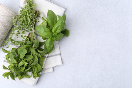 Different fresh green herbs and twine on light table, flat lay. Space for textの写真素材