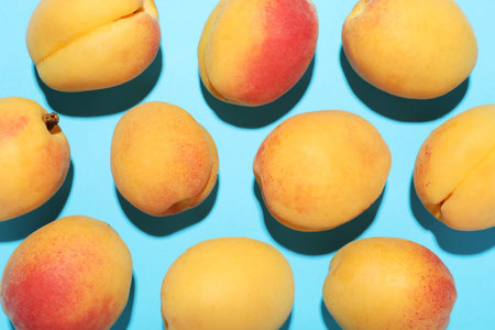 Fresh ripe apricots on light blue background, flat lay