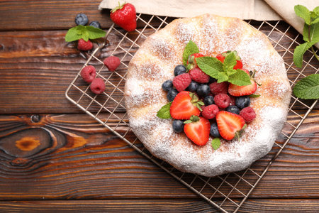 Tasty Bundt cake with powdered sugar and berries on wooden table, flat lay. Space for textの写真素材