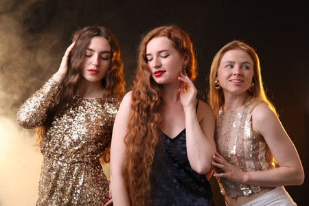 Beautiful women with different hair colors on dark background with smokeの写真素材