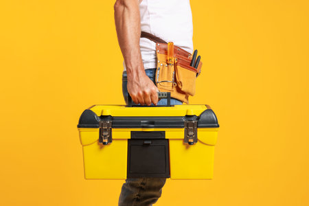 Professional repairman with tool box on orange background, closeupのeditorial素材