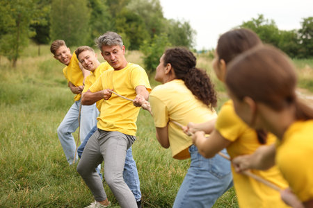 Team building. Group of happy people playing tug of war with rope outdoorsの写真素材