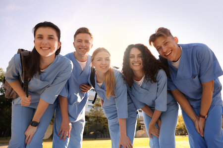 Group of medical students in uniforms with backpacks outdoors, low angle view