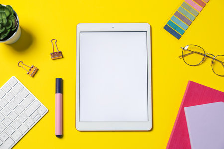 Tablet, glasses, computer keyboard, different stationery and floral decor on yellow background, flat layの写真素材