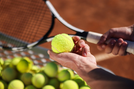 Man taking tennis ball out of cart at court, closeupの写真素材