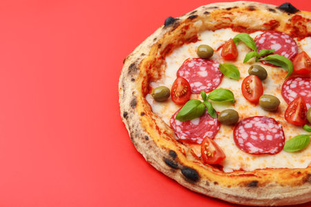 Delicious pizza with salami, olives, tomatoes and basil on red table, closeup. Space for textの写真素材