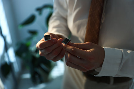 Man with cufflinks getting ready indoors, closeup. Space for textの写真素材