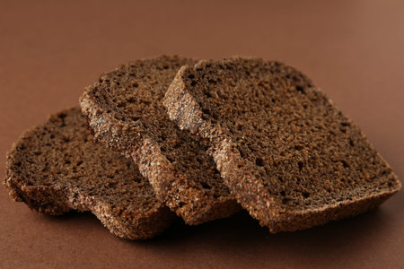 Pieces of fresh rye bread on brown background, closeupの写真素材