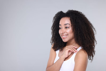 Beautiful Brazilian woman with healthy skin on gray background. Space for text