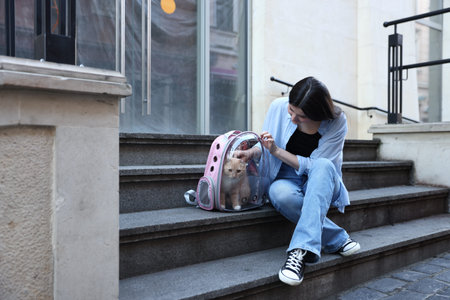 Woman with her cute cat in backpack carrier on stairs outdoorsの写真素材