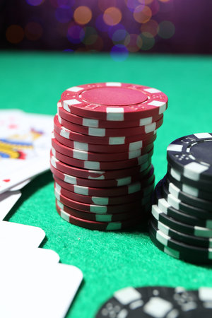 Casino chips and playing cards on green table, closeup