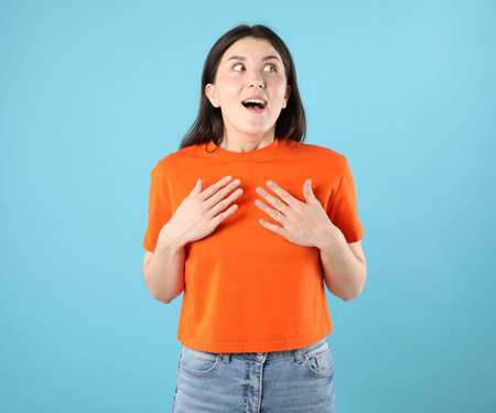 Portrait of surprised woman on light blue backgroundの写真素材