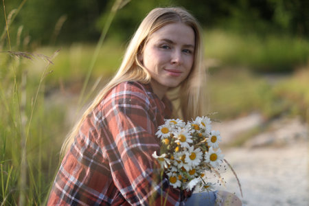 Beautiful woman with bouquet of wildflowers in meadowの写真素材