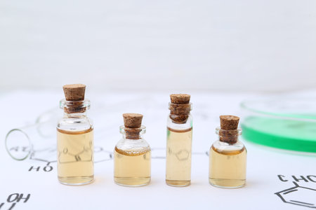 Bottles of cosmetic products, test tube and Petri dish of sample on paper with chemical formulas,...