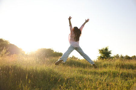 Feeling freedom. Woman jumping in nature, back viewの写真素材