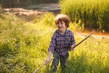 Cute little boy playing with wooden sticks in natureの写真素材