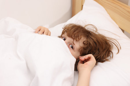 Little boy lying in bed at homeの写真素材