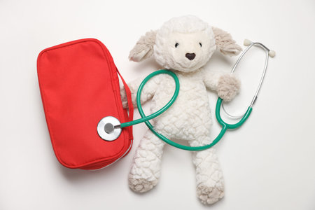 Pediatrics concept. Toy sheep with stethoscope and first aid kit on white background, top viewの写真素材