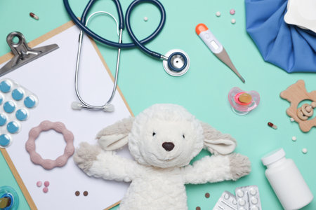 Pediatrics concept. Toy sheep with stethoscope, thermometer, clipboard and pills on turquoise background, flat layの写真素材