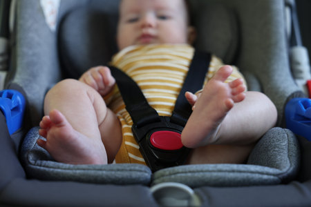 Cute little baby fastened in car seat, selective focus
