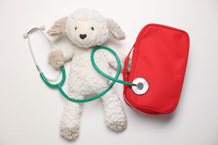 Pediatrics concept. Toy sheep with stethoscope and first aid kit on white background, top viewの写真素材