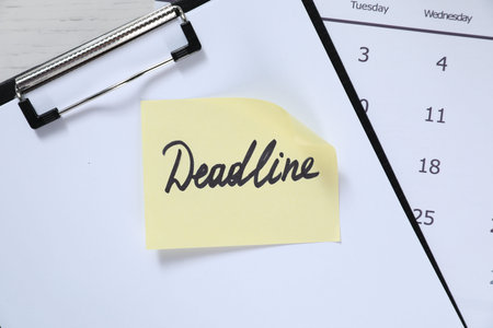 Sticky note with word Deadline, clipboard and calendar on table, top viewの写真素材