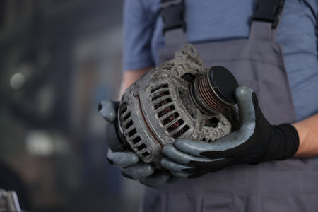 Auto part. Professional mechanic with alternator near indoors, closeup. Space for textの写真素材