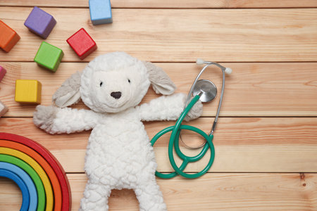 Pediatrics concept. Toys and stethoscope on wooden background, flat lay. Space for textの写真素材