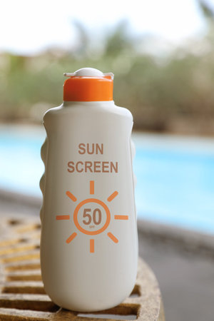 Sunscreen in bottle near swimming pool. Sun protection product