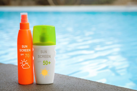 Sunscreens in bottles on swimming pool edge. Sun protection product