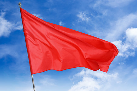 Red flag waving against blue sky outdoors