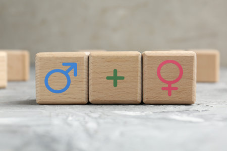Sex education. Wooden cubes with female and male gender symbols and plus sign on table