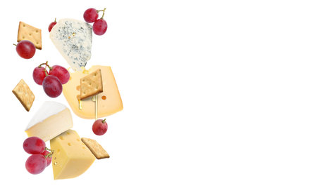 Cheese board products in air on white background. Different types of cheese, grapes, crackers and honeyの写真素材
