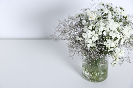Beautiful flowers in vase on white table, space for textの写真素材