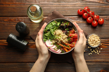 Healthy vegetarian food. Woman with delicious Buddha bowl and ingredients at wooden table, top viewの写真素材