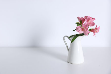 Beautiful flowers in vase on white table, space for textの写真素材