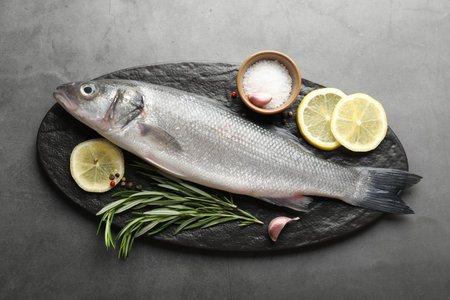 Fresh raw seabass with spices on grey table, top view. Fish and seafood delicaciesの写真素材
