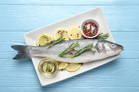 Fresh raw seabass with spices on blue wooden table, top view. Fish and seafood delicaciesの写真素材