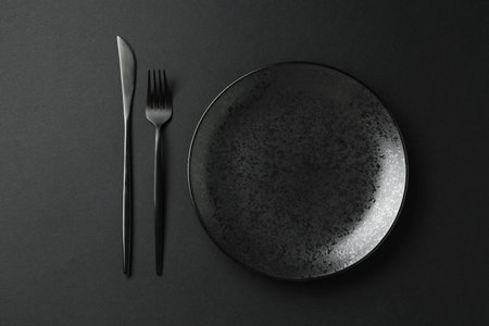Stylish plate and cutlery on black background, flat layの写真素材