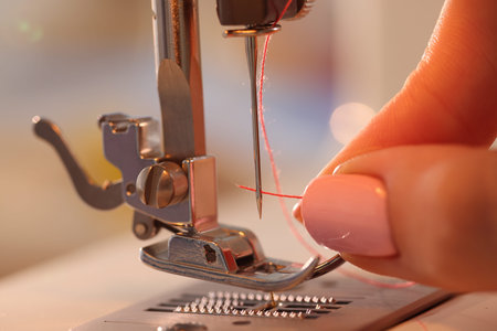 Woman working with sewing machine in workshop, closeup