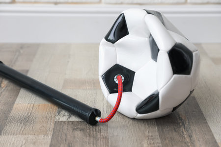 Soccer ball and manual air pump indoors, closeup