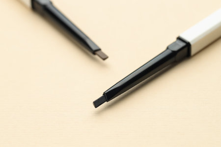 Automatic eyebrow pencils on beige background, macro viewの写真素材