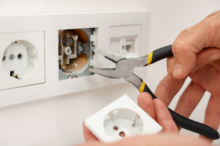 Man fixing power sockets with pliers indoors, closeup