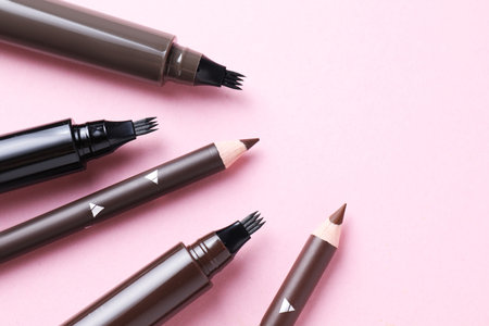Different eyebrow pencils on pink background, closeup. Space for textの写真素材